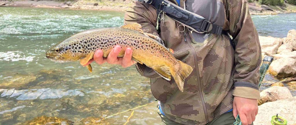 Explore The Essentials Of Fly Fishing - What is tippet and how to use it, man holding a fish that he caught with fly fishing in natural river